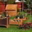 Vegetable garden with wooden structures and labeled plant beds in a backyard.