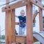 Child playing on Etna wooden playground structure with a slide.