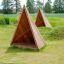 Wooden Tipi Nature play tents on grassy playground area