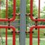 Red climbing structure of Shea playground equipment in a green park.