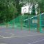 Outdoor basketball court with green metal fences, featuring the Shea basketball setup.