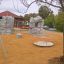 Carousel playground equipment in a sandy area with artificial climbing rocks in the background.