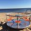 Carousel playground equipment on a sandy beach with a sea view.