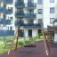 Bird Nest (âŚ€ 90 cm) Wooden Swing hanging in modern playground near residential buildings.