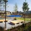 Single Swing (BNS 90cm) in a modern outdoor playground surrounded by greenery and seating areas.
