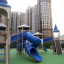 Citadel castle with slide in modern playground near tall apartment buildings