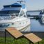 Saint-Tropez Deck Chair on grass near luxury yachts at a marina.