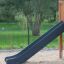 Slide from Romping Corner Nature playground set in a sandy play area with greenery in the background