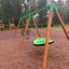 Green Swing Seat GBNS on a wooden playground set in a park.