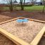 Butterfly Play Table installed in a sandbox with a wooden frame.