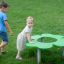 Children playing around Clover Play Table in a park.