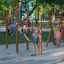 Children playing on wooden pull up bars in a sunny outdoor playground