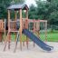 Wooden playground structure Romping Cottage with slide and climbing net.