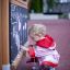 A toddler drawing on a Blackboard in a playground.