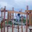 Child playing on Etna wooden playground structure with climbing net.