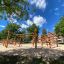 Sonora wooden playhouse in a sunny park with trees and blue sky.