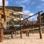 Sonora wooden playhouse on a sandy playground with climbing ropes and wooden beams.