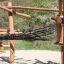Sonora wooden playhouse with wooden beams and net bridge in an outdoor playground.