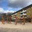 Sonora wooden playhouse in a playground with apartment buildings in the background.