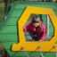 Child playing in Alice's house playground equipment.