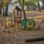 Outdoor playground equipment for children in a park surrounded by trees - Aliceâ€™s house.