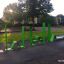 Outdoor fitness equipment Ribbon Fitness II in vibrant green color, installed in a park setting.