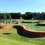 Multiarena Wooden outdoor sports facility with basketball hoops and green turf.
