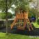 Hexagon Modern Nature II single slide playground structure in a park setting with trees and grass.