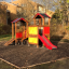 Knight's Castle playhouse with slide in a playground setting.