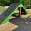 Wooden tent playhouse with climbing wall for children.