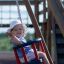 A child enjoying a ride on the Baby Single Swing at a playground.