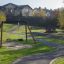 Double Swing playground structure with a tire and traditional seat in a park with pathways and color
