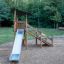 Elbrus wooden playground slide with metal chute in forest setting