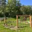 Outdoor wooden 'Obstacle course' in a green park with climbing nets and balance beams.