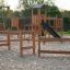 Trim trail wooden playground equipment with climbing elements and slide on sandy ground