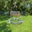 Bicycle merry-go-round in a playground setting with green grass and trees in the background.