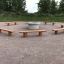 Robinia bench set around a central fire pit in an outdoor park area.