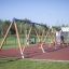 2+2 multiple swing set on a playground with rubber flooring and climbing wall in the background