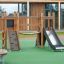 Mini Play II playground equipment with slide and climbing wall on a green safety surface