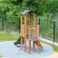 Pixie Modern Nature wooden playground tower with slide and climbing net on safety surface