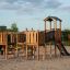 Wooden Challenger Modern Nature playground structure with slide on sandy surface.