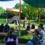 Children learning outdoors under Picnic Shelter w/ Blackboard on playground benches