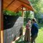 Wooden Picnic Shelter w/ Blackboard with two people interacting outdoors on a sunny day