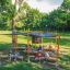 Outdoor Classroom with wooden benches, sunshades, blackboard and plant pots in a green park setting.