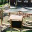 Outdoor Classroom with wooden benches, sunshades, blackboard, and plant pots in playground setting.