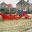Small Ship sandbox with red slide and climbing structure in playground.