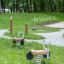 Two Bike rocking toys in a park with a grassy area and trees in the background.