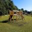 Alstad Eco wooden playground climbing structure with slide and rope bridge on grassy field