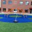 Playground equipment Spinner II with orange arches and a central spinning pole on a blue and green s