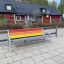Colourful bench with rainbow slats on metal frame in outdoor setting.